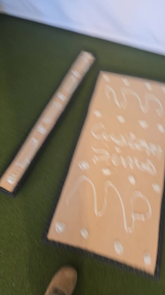 Custom Sims branded hitting mat beside an indoor putting green