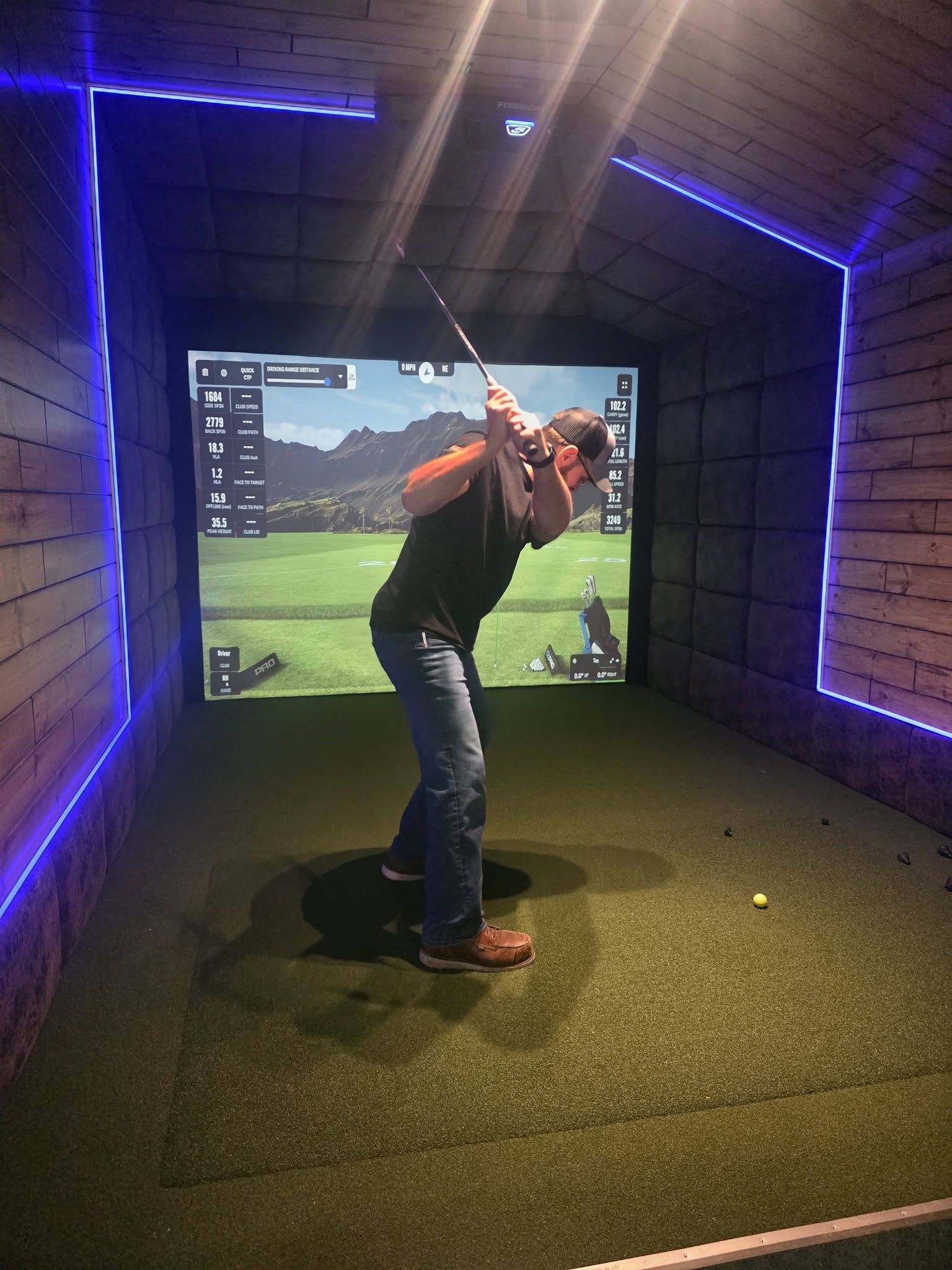 Golfer mid-swing in front of a pro-grade impact screen